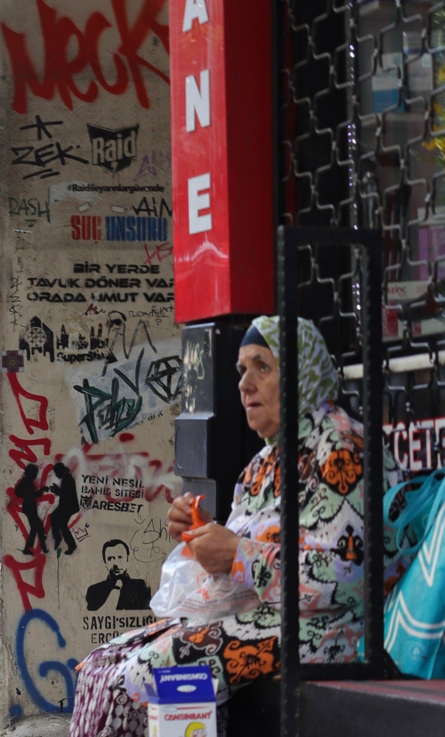 Woman sitting in a chair with a colorful pattern, surrounded by graffiti on a wall.